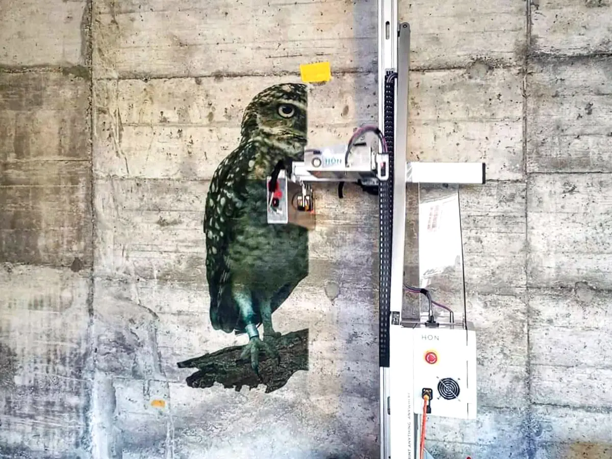 An image of an owl is in the process of being printed on a concrete wall